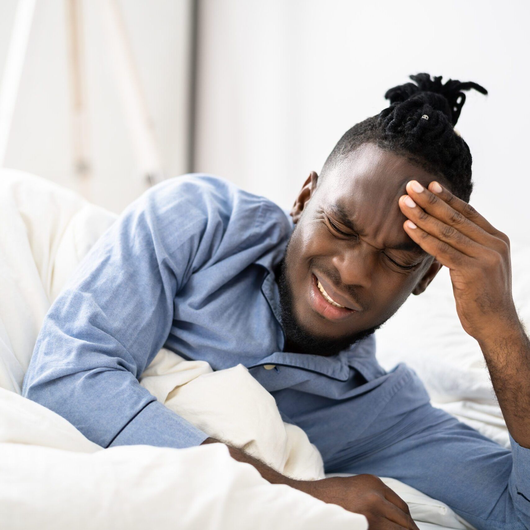 Sick African American Man With Headache In Bed
